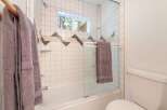 This bathroom features a classic white tiled shower-tub combo with a decorative geometric accent band.