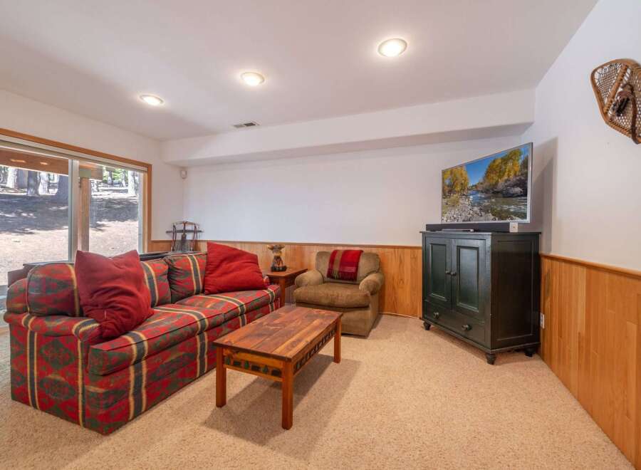 Cozy up in this inviting living room featuring a patterned sofa with plush red throw pillows and a matching armchair.