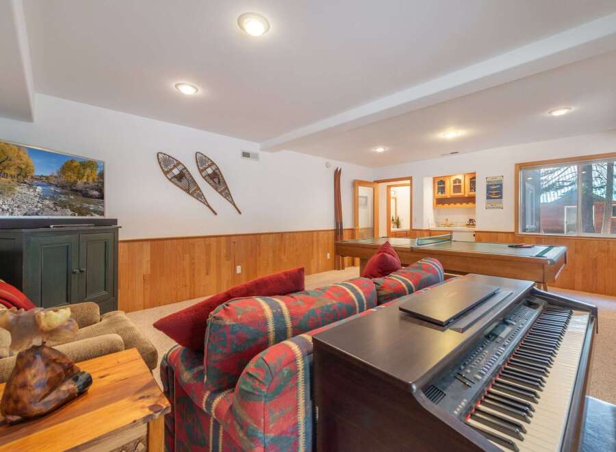 This basement living area offers a perfect blend of entertainment and relaxation, featuring a large flat-screen TV, a pool table, and a ping pong table.