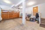 Discover ample storage and functionality in this spacious garage, featuring a large wooden garage door and convenient shelving units.