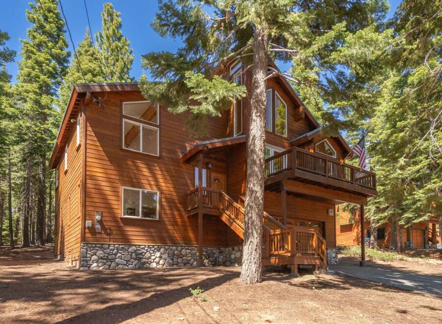 Nestled among tall pine trees, this charming wooden cabin offers a rustic retreat with a stone foundation and multiple levels of living space.
