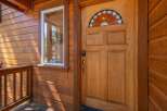 Step into this charming cabin-style home, featuring a beautiful wooden door with a stained-glass transom window that adds a touch of elegance.