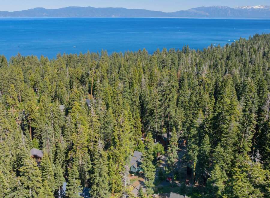Nestled amidst a dense forest, this property offers a serene escape with stunning views of a vast blue lake and distant mountains.