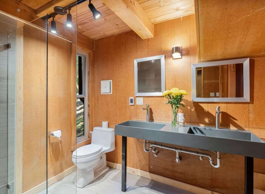 Experience rustic charm in this unique bathroom featuring a dual basin concrete vanity and a modern toilet.