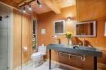 Experience rustic charm in this unique bathroom featuring a dual basin concrete vanity and a modern toilet.