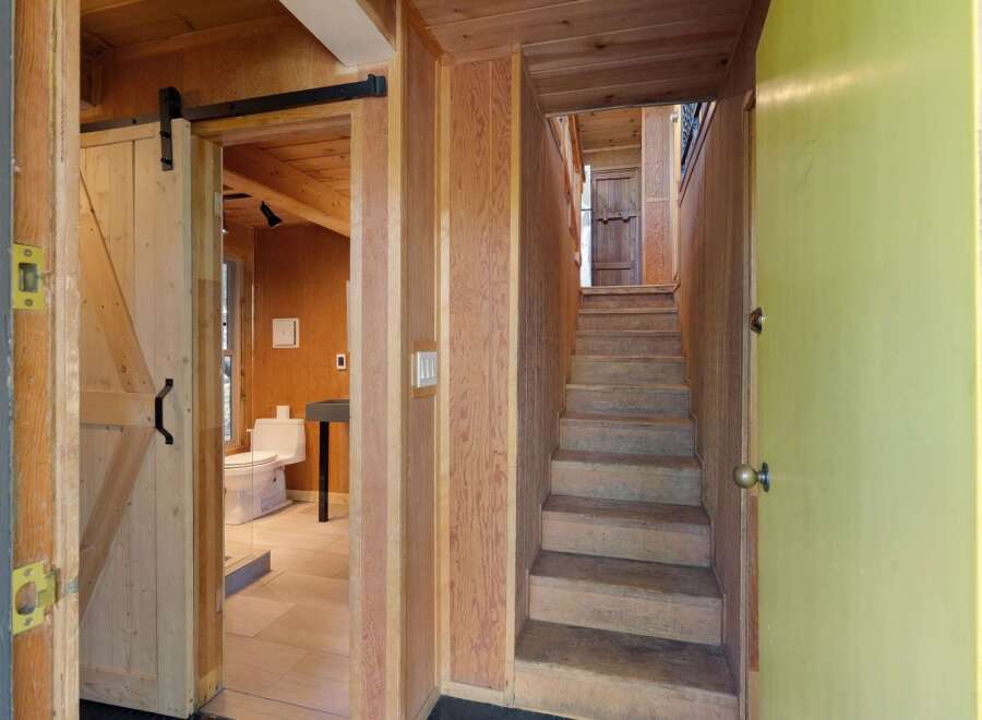 Discover unique charm in this home featuring a rustic barn door leading to a modern bathroom with a toilet and sink.