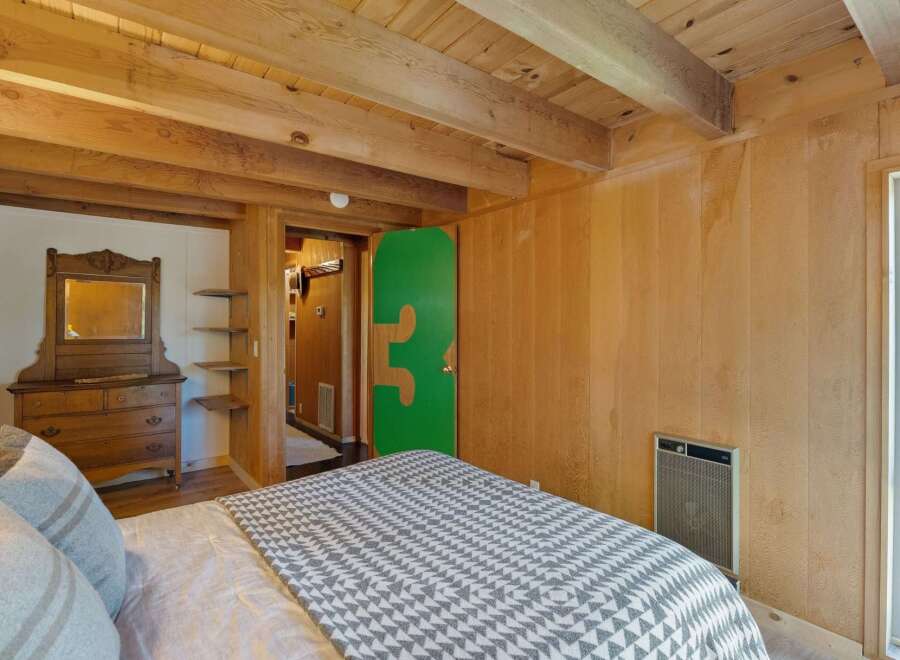 Experience rustic charm in this cozy bedroom featuring warm wood paneling and exposed beams.