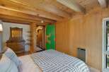 Experience rustic charm in this cozy bedroom featuring warm wood paneling and exposed beams.