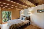 Experience serene living in this charming bedroom, featuring a cozy bed adorned with a geometric-patterned blanket and plush pillows.