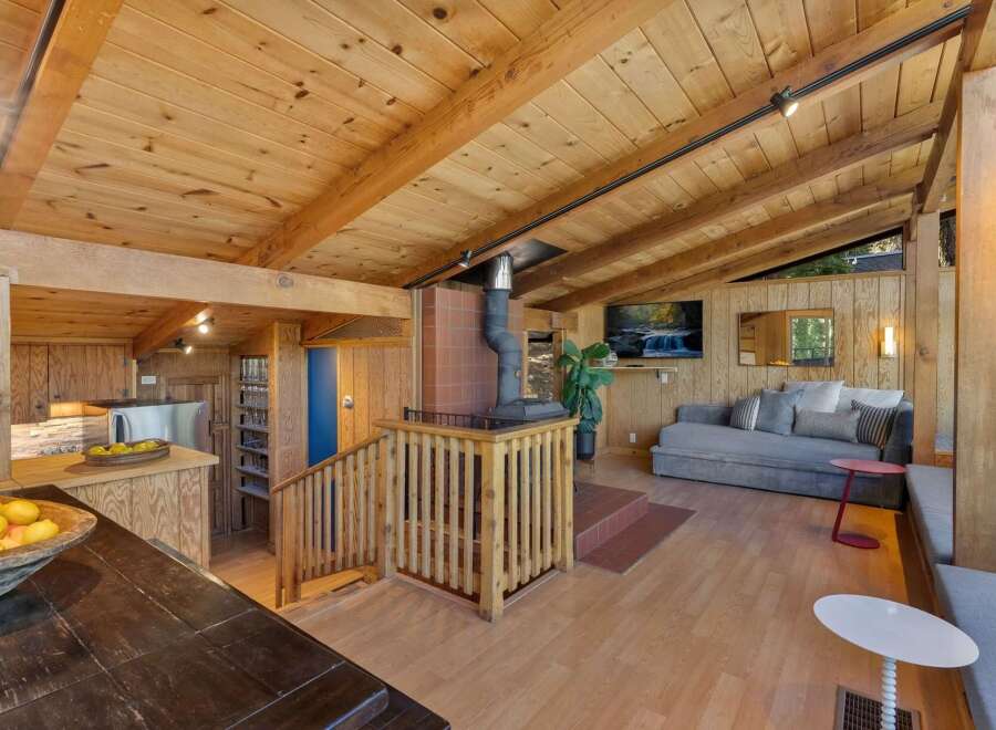 Experience rustic charm in this inviting living space featuring a prominent wood-burning stove and vaulted wood-paneled ceilings.