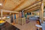 Experience rustic charm in this inviting living space featuring a prominent wood-burning stove and vaulted wood-paneled ceilings.