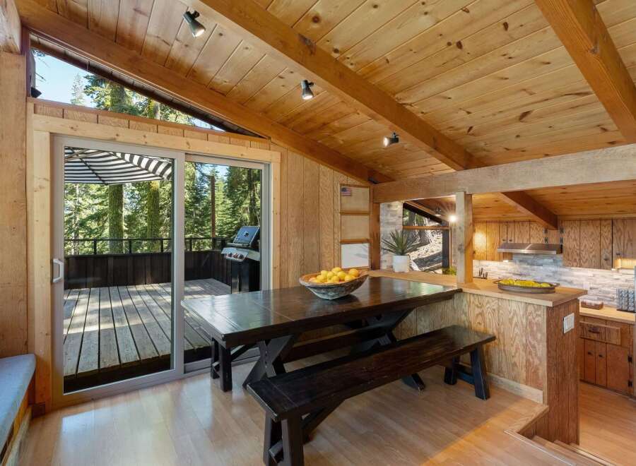 Experience rustic charm in this mountain retreat, featuring a spacious dining area with a wooden picnic table and benches, perfect for gathering.