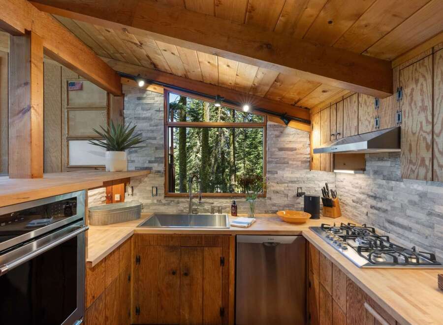 Experience rustic charm in this cozy kitchen featuring natural wood cabinetry and a stone tile backsplash.