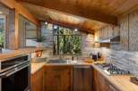 Experience rustic charm in this cozy kitchen featuring natural wood cabinetry and a stone tile backsplash.