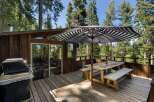 Enjoy outdoor dining and grilling on this spacious wooden deck, perfect for entertaining guests amidst a serene forest setting.