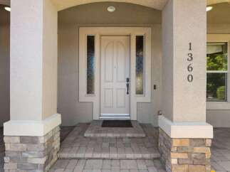Welcome to this charming home featuring a beautiful arched entryway with decorative sidelights framing the elegant front door.