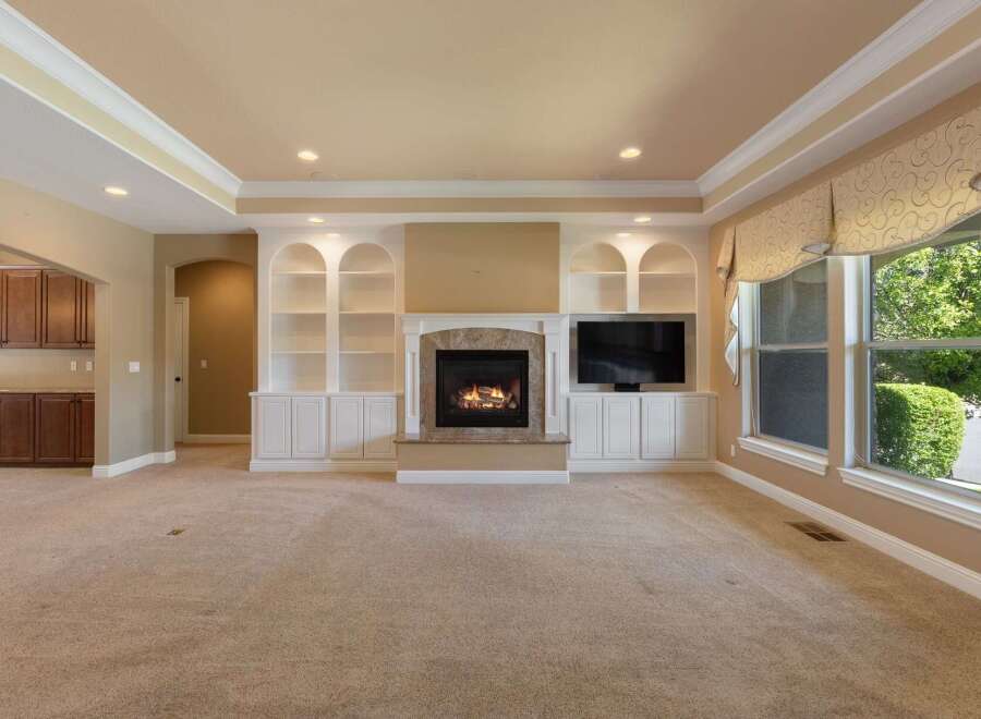 This spacious living room features a cozy fireplace with built-in shelving and a large television, perfect for entertaining.