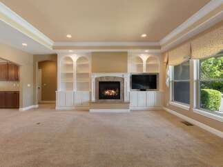 This spacious living room features a cozy fireplace with built-in shelving and a large television, perfect for entertaining.