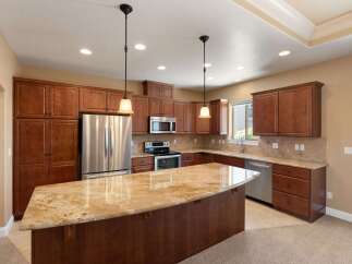 Experience luxury in this stunning kitchen featuring rich cherry wood cabinetry and a spacious granite island perfect for entertaining.
