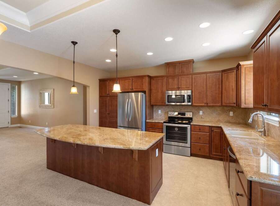 This spacious kitchen boasts rich cherry wood cabinetry and elegant granite countertops, perfect for the home chef.