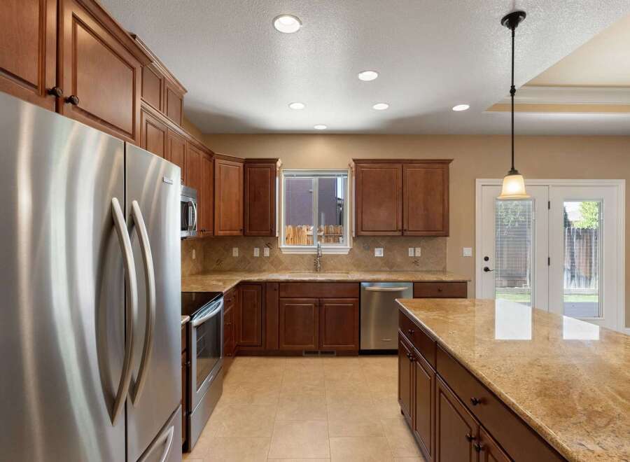 This spacious kitchen boasts rich cherry wood cabinetry and gleaming granite countertops, offering ample storage and workspace.