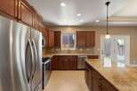 This spacious kitchen boasts rich cherry wood cabinetry and gleaming granite countertops, offering ample storage and workspace.