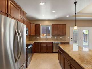 This spacious kitchen boasts rich cherry wood cabinetry and gleaming granite countertops, offering ample storage and workspace.