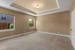 This spacious bedroom features a beautiful tray ceiling with elegant crown molding and a central light fixture.