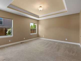 This spacious bedroom features a beautiful tray ceiling with elegant crown molding and a central light fixture.