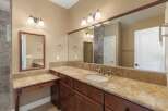 This spacious bathroom features a double vanity with granite countertops and rich wood cabinetry, offering ample storage.