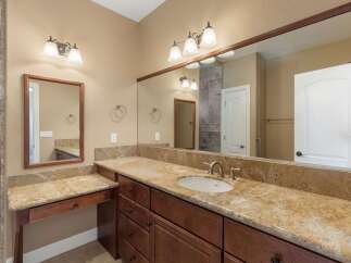 This spacious bathroom features a double vanity with granite countertops and rich wood cabinetry, offering ample storage.