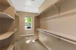 Discover ample storage in this spacious walk-in closet, featuring built-in shelving and multiple hanging rods.