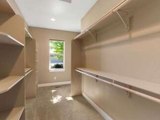Discover ample storage in this spacious walk-in closet, featuring built-in shelving and multiple hanging rods.