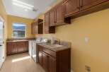 This spacious laundry room features ample storage with custom wood cabinetry and granite countertops.