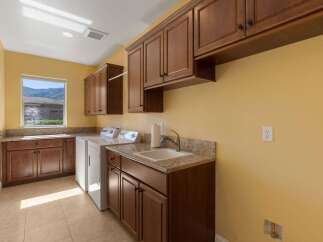 This spacious laundry room features ample storage with custom wood cabinetry and granite countertops.