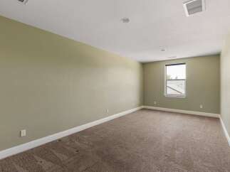This spacious room features neutral-toned walls and plush carpeting, creating a serene and inviting atmosphere.