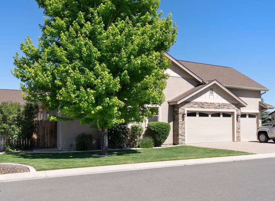 Discover this charming home featuring a lush green lawn and a mature tree providing ample shade.