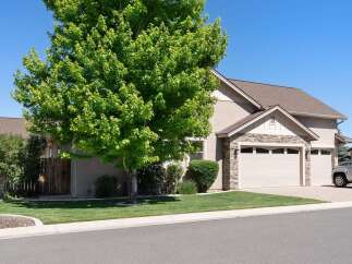 Discover this charming home featuring a lush green lawn and a mature tree providing ample shade.