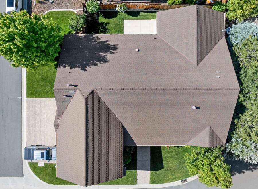 Discover this stunning aerial view of a well-maintained home featuring a durable brown shingle roof.