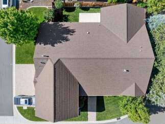 Discover this stunning aerial view of a well-maintained home featuring a durable brown shingle roof.