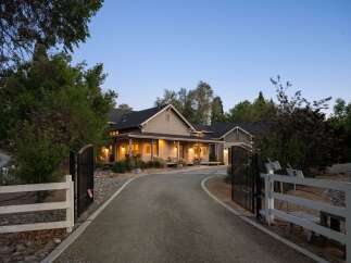 Discover this stunning property featuring a charming farmhouse-style home with a welcoming wrap-around porch, perfect for enjoying the serene surroundings.