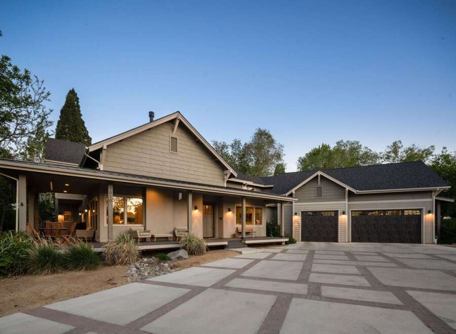 This stunning home features a welcoming covered porch with ample seating, perfect for enjoying the outdoors.