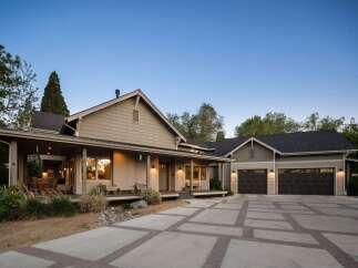 This stunning home features a welcoming covered porch with ample seating, perfect for enjoying the outdoors.