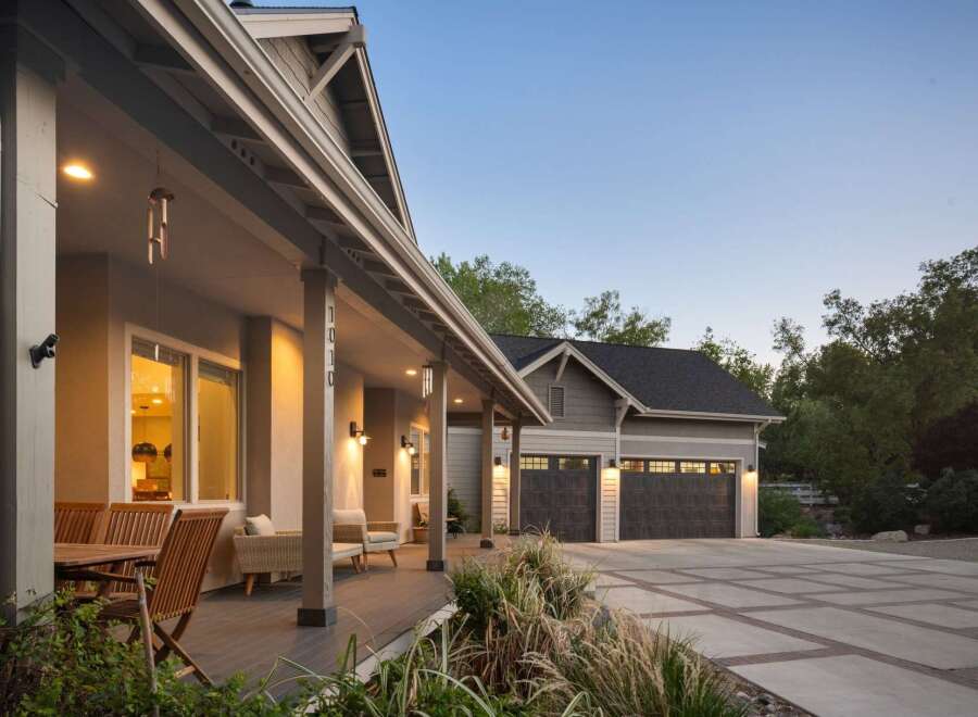 This stunning home features a welcoming covered porch with comfortable seating and a dining area, perfect for enjoying the outdoors.