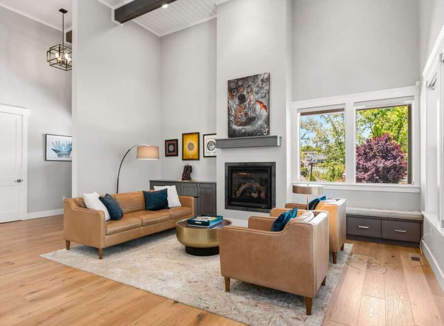 Experience luxury living in this stunning living room, featuring a grand fireplace as the centerpiece and a soaring vaulted ceiling with exposed beams.