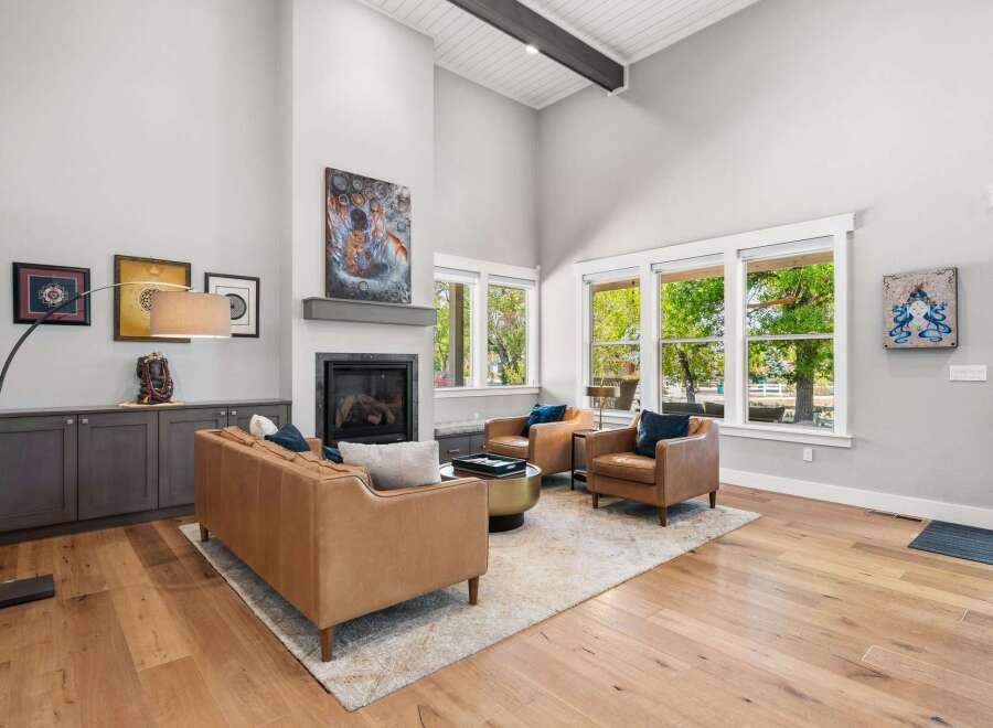 Experience luxury living in this stunning great room, featuring a soaring vaulted ceiling with exposed beams and a modern fireplace as the focal point.