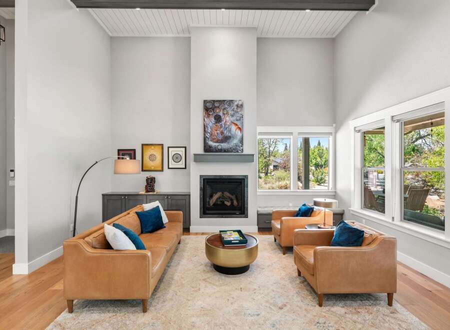Experience luxury living in this stunning great room, featuring a soaring vaulted ceiling with exposed beams and a modern fireplace as the focal point.