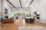 Experience modern luxury in this stunning open-concept living space, featuring a soaring vaulted ceiling with exposed beams and abundant natural light.