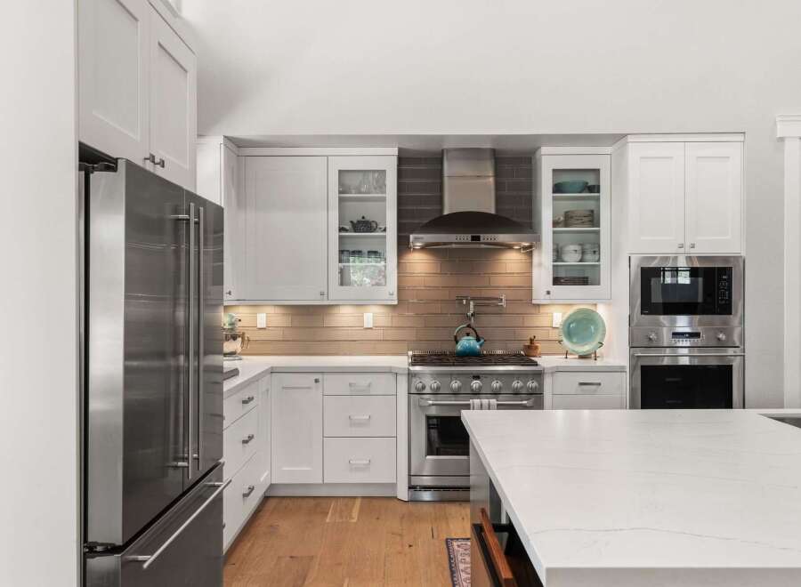 Experience culinary excellence in this stunning modern kitchen, featuring sleek white cabinetry and a professional-grade stainless steel range.
