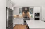 Experience culinary excellence in this stunning modern kitchen, featuring sleek white cabinetry and a professional-grade stainless steel range.